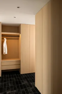 Modern closet space with wooden cabinets and black tiled flooring.