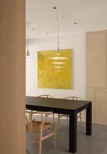 Modern dining room with a wooden table and chairs, featuring a yellow artwork hanging above the table.