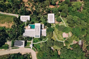 Aerial view of a modern residential house with concrete and glass materials.