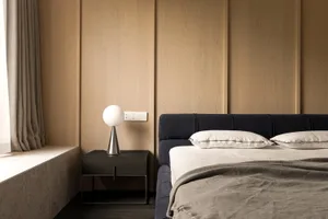 Modern bedroom with minimalist design, wood paneling, and a sleek, spherical lamp on a nightstand.