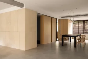 A minimalist dining room featuring wooden furniture and light-colored walls.