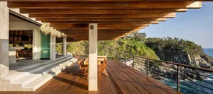 Modern deck overlooking the ocean with wooden flooring and railings.
