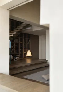 A minimalist residential space featuring wooden stairs with books and lamps.