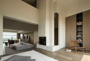 Modern living room featuring concrete and glass walls, accompanied by a wooden furniture set and a cozy fireplace.