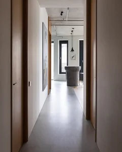 現代簡約走廊，混凝土地板與牆面，搭配嵌入式燈具與石材基座。