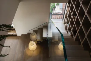 A modern staircase with wooden steps, glass railings, and two pendant lights providing ambient lighting.