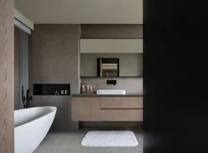 Modern minimalist bathroom with concrete walls, floating wooden vanity, and freestanding bathtub.