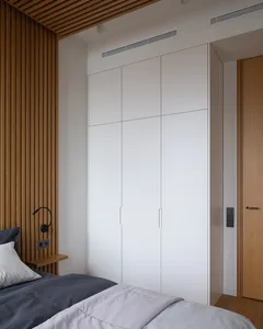 A minimalist bedroom with a bed, white walls, and wooden accents.