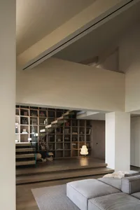 A modern library with a staircase, featuring a minimalist design with wooden elements and a glass railing.