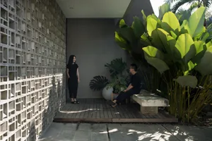 A modern concrete veranda with a woman and a man sitting on benches.