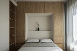 A modern minimalist bedroom with a bed, pillows, and a vase of flowers on a headboard.