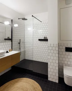Modern minimalist black and white bathroom with a walk-in open shower, white subway tiles, black accents, and a floating wood