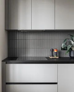 A minimalist kitchen with gray tiles on the backsplash and cabinets.
