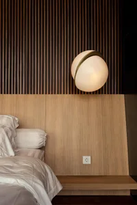 Modern bedroom featuring a wooden floating headboard with a spherical pendant lamp and white bedding.