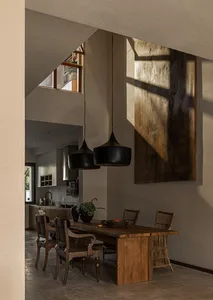Modern dining room featuring wooden furniture, pendant lights, and a large abstract painting.