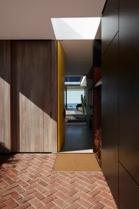 Modern entrance with a wooden floor and a yellow door leading to an outdoor space.