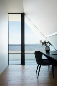 Modern home office with glass window overlooking the ocean.