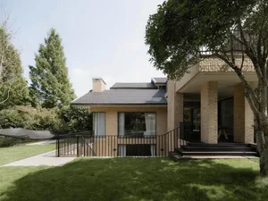 Modern house exterior with brick, glass, and wood materials in the backyard.