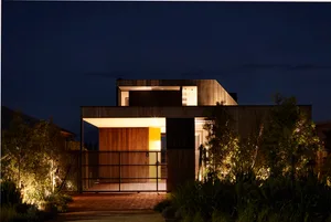 A modern residential house at night with warm interior lights and external lighting features.