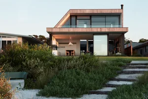 A modern house with a wood frame and large glass panels on the exterior.