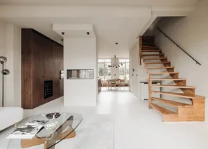 Modern residential kitchen and dining area with wood stairs and concrete flooring.
