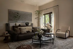 Modern living room featuring a cozy couch with accent pillows, a round coffee table, and natural light through a large window