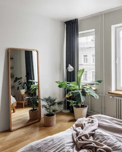 Minimalist bedroom featuring plants and a large floor mirror.