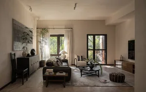 Modern living room featuring neutral-toned furniture and decor, large windows with natural light, and a cozy ambiance.