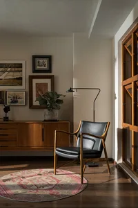 A cozy mid-century modern living room with wood, leather, and glass elements.