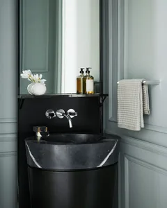 Modern bathroom interior with black marble sink, metal faucet, and minimalist design.