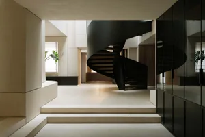 Modern black spiral staircase with white railings in an interior setting.