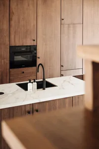 A modern kitchen featuring wooden cabinets and a marble countertop.