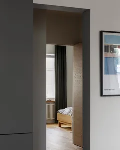 A minimalist bedroom featuring wooden furniture and fabric bedding.