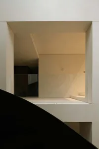 A minimalist library with white walls, glass walls, and exposed concrete floors.