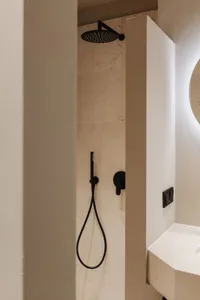 Modern, minimalist bathroom with marble tiles and black fixtures.