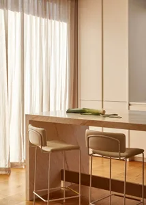 A modern, minimalist kitchen interior featuring a marble counter and sleek bar stools.
