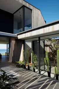 Modern house exterior with wooden veranda and large windows.