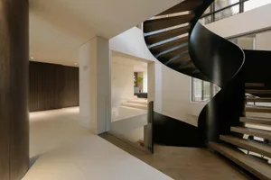 A modern interior design featuring a black metal spiral staircase.