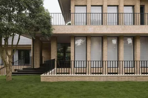 A modern house exterior made of brick with large windows and a balcony.
