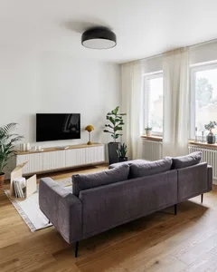 A modern living room with a dark gray sofa, minimalistic decor, and neutral-toned color palette.