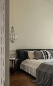 A modern minimalist bedroom with gray textiles and a black leather upholstered bed frame.