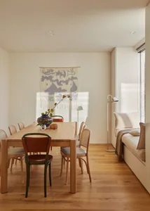 A minimalist dining room featuring a wooden table and chairs.