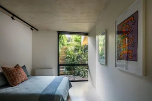 Minimalist bedroom with a window offering a view of greenery and stairs.