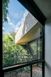 An architectural view showing a modern exterior with a combination of concrete and glass materials, seen through a window.