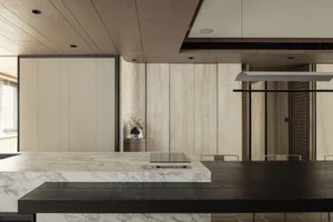 Modern minimalist interior space featuring a wooden kitchen counter and dining table with a minimalist design.