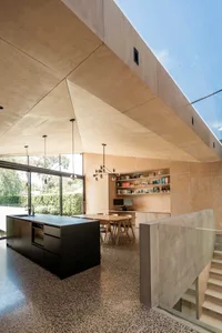 A modern residential interior featuring a concrete floor, plywood ceiling, and black kitchen island.