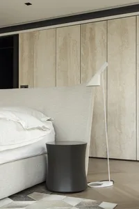Minimalist bedroom featuring fabric bed, wooden cabinet, and metal lamp.