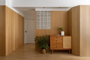 極簡室內空間，展示木質層架與抽屜，木地板上擺放盆栽與裝飾花瓶。