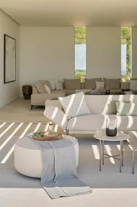 A minimalist living room featuring fabric sofas, glass coffee tables, and concrete flooring and walls.