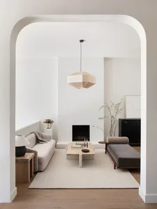 Modern, minimalist living room with neutral-colored furniture and a geometric lamp.